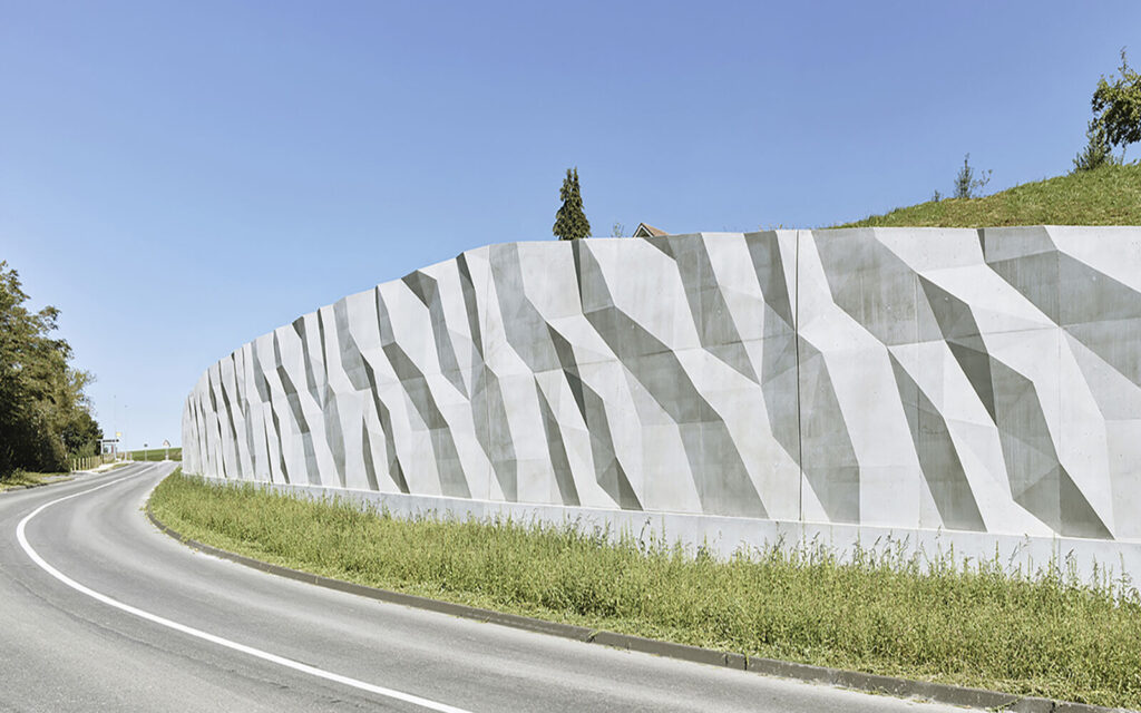 Um den Verkehr, die Sicht und die Sicherheit der Strasse zu verbessern, wurde das Architekturbüro Baraki vom Kanton Fribourg beauftragt, eine Stützmauer entlang der neuen Kantonsstrasse Riderberg - Bösingen zu gestalten. (Foto: Betonsuisse)