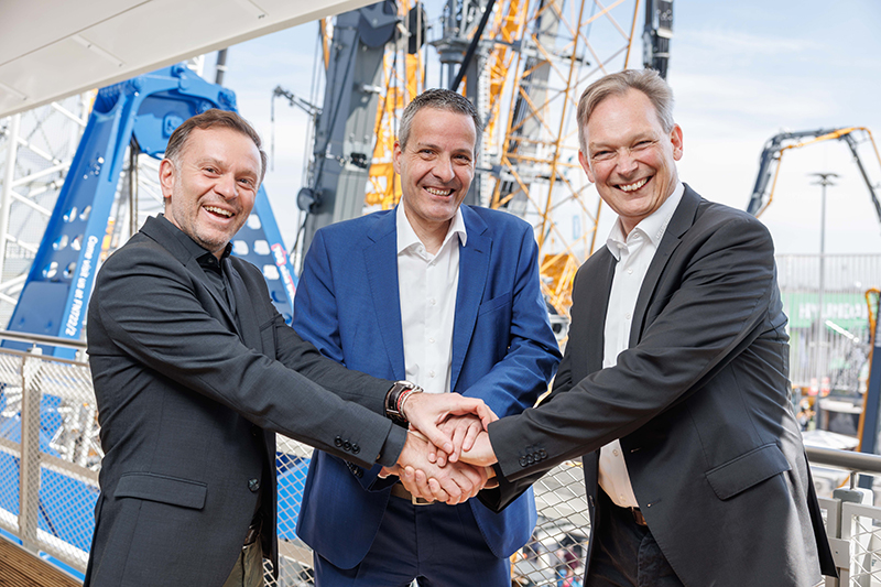 Claus von Reibnitz, Head of Control Systems & Connectivity bei Liebherr (rechts), Pascal Rey, CEO von Reycom (mitte), sowie Eric Mazzoleni, Vice President, Industrial and Embedded IoT Sales – Europe bei Qualcomm Germany GmbH (links), besiegeln die Partnerschaft auf der Bauma 2025 in München. (Foto: pd)