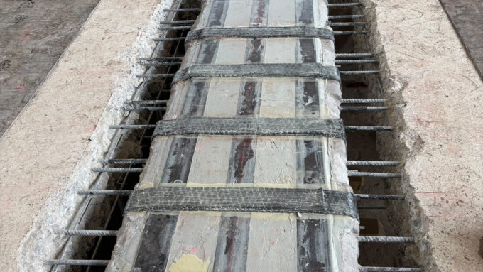 Blick von oben auf die Schubverstärkungen, die den Unterzug durch Durchbrüche umfassen. Dank Hochdruckwasserstrahlen blieb die vorhandene Bewehrung erhalten.