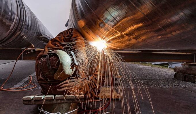 Arbeiter schweisst Elemente der Transportleitung zusammen. (Foto: zvg)